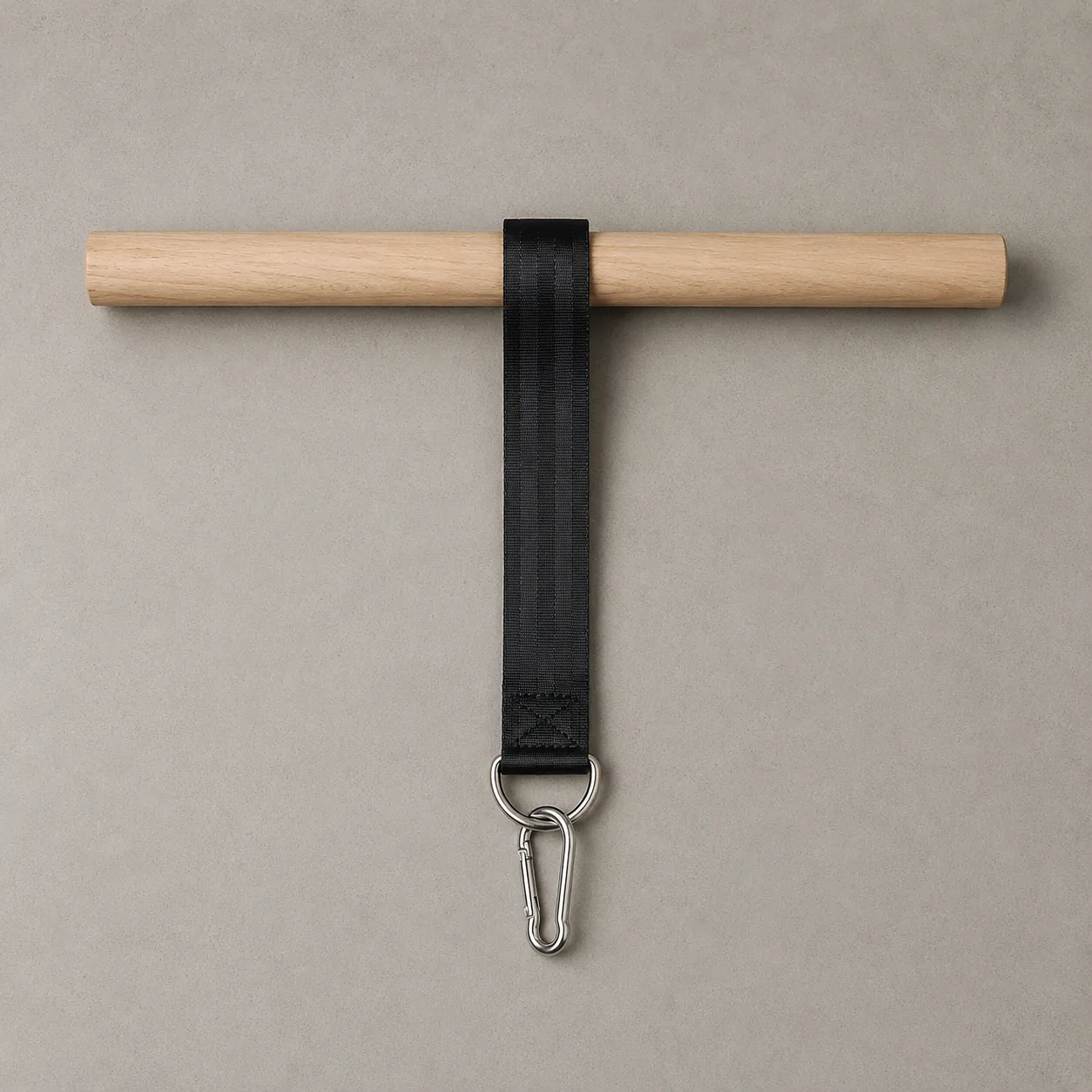 Overhead flat lay of the three parts: wooden bar, flat nylon strap laid out beneath it, steel D-ring and carabiner